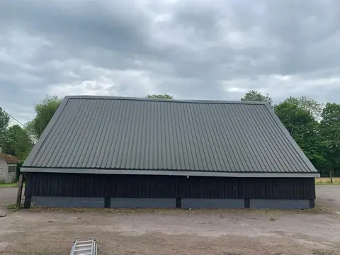 The same barn roof after overcladding, finished in grey profiled sheets with new verge and eaves trims