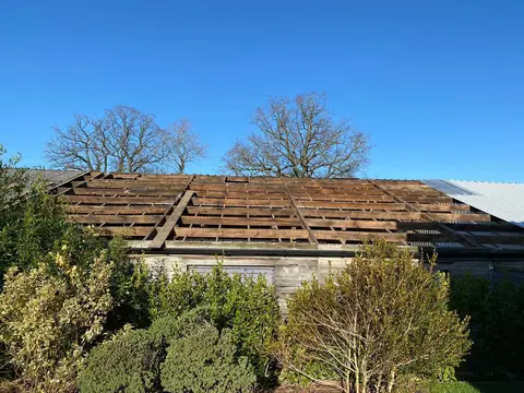Old roof sheets stripped back to the timber purlins, with the first new sheets on at the far end