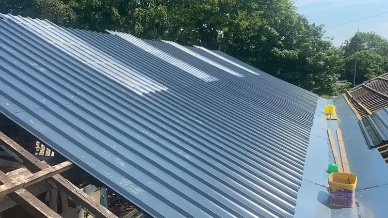 New grey profiled steel roof sheets and rooflights, with the valley gutter between the spans being lined